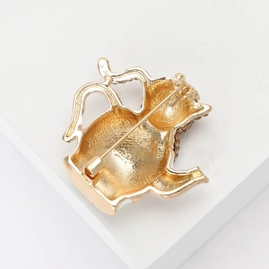 Détail de la broche théière en métal doré avec fermoir à épingle et strass brillants