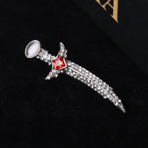 Macro shot of silver sword brooch with sparkling white rhinestones and a red center gem