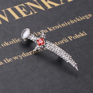 Elegant dagger brooch with rhinestones and red gem on vintage black background