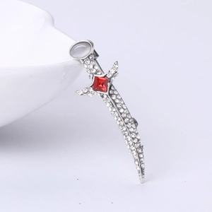Macro shot of a silver sword brooch featuring sparkling rhinestones and a red square gem