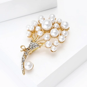 Dettaglio dell'elegante spilla a bouquet di perle dorata con fiocco di strass