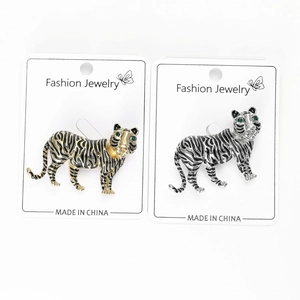 Detailed view of vintage gold and silver tiger brooches with green gemstone eyes