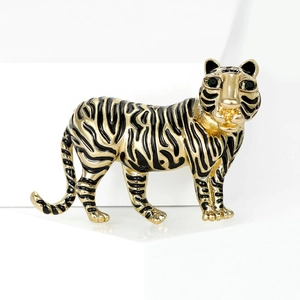 Vintage gold tiger brooch with black enamel and green gemstone eyes on white background