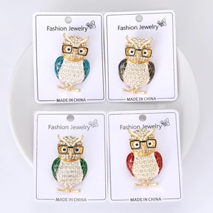Detailed macro view of four colorful owl brooches with enamel wings and crystal rhinestones
