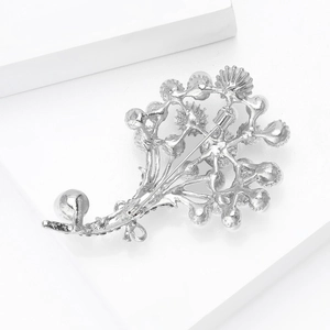 Dettaglio della spilla a fiore argento che mostra la chiusura a perno e il retro in metallo