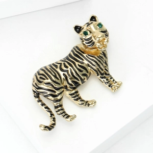 Detailed view of vintage gold tiger brooch with black enamel stripes and green gemstone eyes