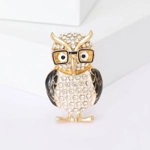 Sparkling owl brooch with rhinestones and black enamel on a minimalist white stand