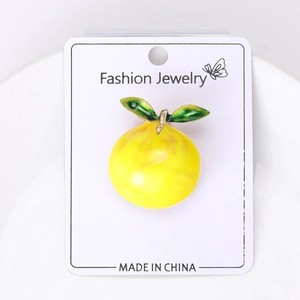 Detail of yellow fruit lemon brooch with green leaves and gold metal on a display card