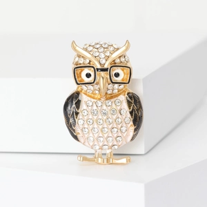 Elegant owl brooch with sparkling rhinestones and golden metal finish on white background