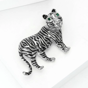 Close-up of tiger brooch with silver metal finish, black enamel and green gemstone eyes