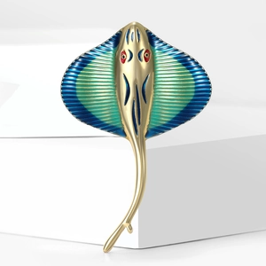 Macro shot of gold alloy stingray brooch with blue-green enamel and red crystal eyes