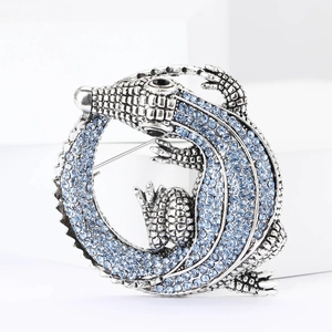 Detailed close-up of a silver crocodile brooch with sparkling blue rhinestones