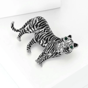 Detailed close-up of tiger brooch with silver metal, black enamel and green gemstone eyes