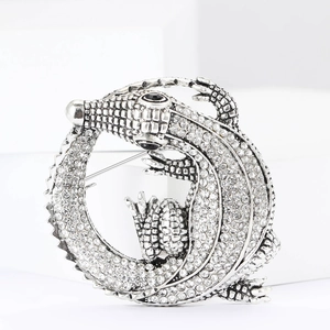 Detailed close-up of a silver-tone alloy crocodile brooch with sparkling white rhinestones