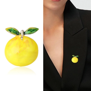 Vibrant yellow lemon fruit brooch with green enamel leaves on a black suit jacket lapel