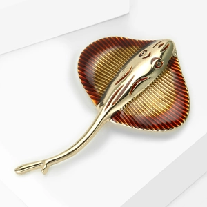 Macro view of golden stingray brooch with detailed amber enamel on a white backdrop