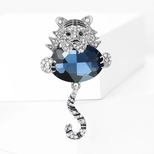 Dettaglio di una spilla a forma di tigre argentata con strass e una grande gemma blu