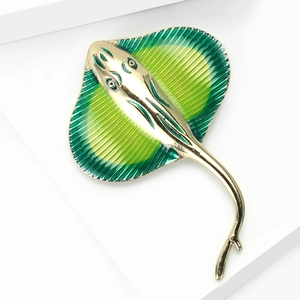 Macro shot of green and yellow gradient enamel stingray brooch with golden alloy details