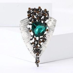 Detail of vintage shield brooch with emerald glass stone and rhinestone accents