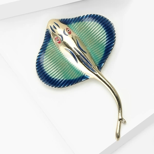 Macro detail of stingray brooch featuring blue-green enamel and gold-plated metal fins