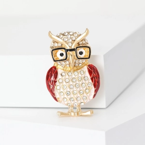 Close-up of sparkling owl brooch with red enamel wings and crystal rhinestones