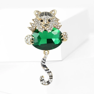 Dettaglio della spilla tigre dorata con diamanti incastonati e grande pietra verde