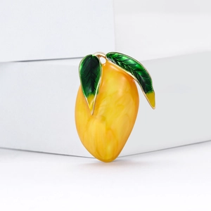 Cute mango brooch pin with yellow marble texture and green leaves on white stand