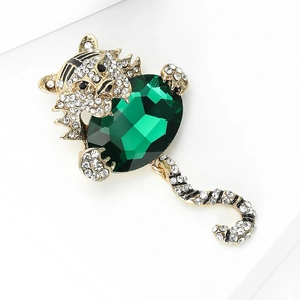 Dettaglio ravvicinato di una spilla a forma di tigre dorata con smeraldo e strass luminosi