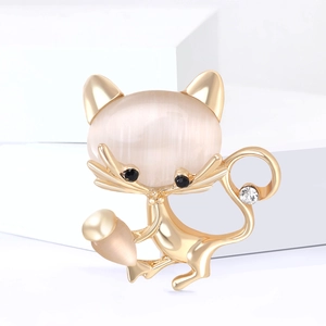 Broche chat dorée avec opale et strass sur supports géométriques blancs