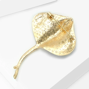 Detailed back view of a golden manta ray brooch featuring intricate star texture and pin