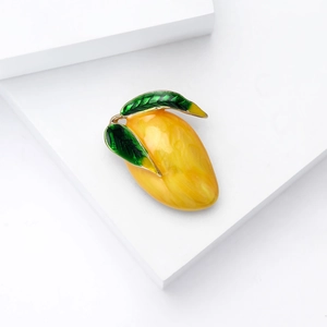Minimalist vibrant yellow mango fruit brooch with green leaves and gold metal plating