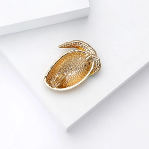 Detail view of the honeycombed metal back and safety pin of a fruit-shaped brooch
