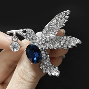 Detailsicht der Kolibri-Brosche in Silber mit großem blauem Kristall und weißen Strasssteinen