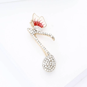 Détail de la broche note de musique avec papillon rouge et strass étincelants