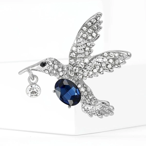 Makro-Detail der silbernen Kolibri-Brosche mit blauem Kristall und weißen Straßsteinen