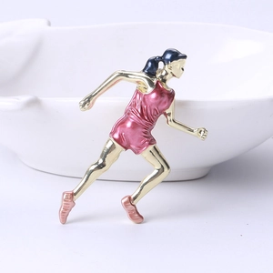 Détail d'une broche athlète en émail rose et métal doré avec une pose de course