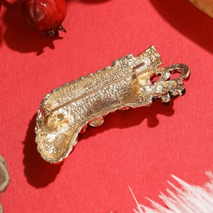 Vintage gold alloy Christmas stocking brooch with red and black details on red background