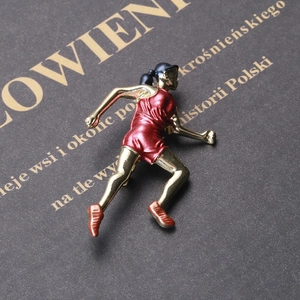 Gros plan d'une broche de fille qui court avec finition émail sur un livre noir élégant