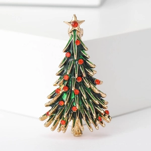 Détail d'une broche sapin de Noël dorée avec émail vert et cristaux de strass rouges