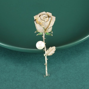 Élégante broche rose dorée avec cristaux étincelants et perle sur fond en céramique verte