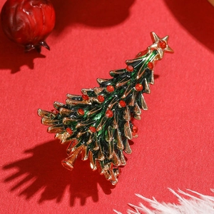 Broche sapin de Noël exquise avec émail vert et strass rouges sur un fond rouge vif