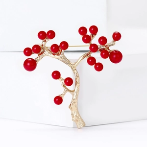 Elegant gold holly berry branch brooch with vibrant red pearls on minimalist pedestal