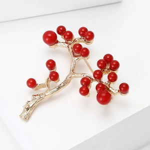 Macro shot of red holly berry brooch with golden metallic stems and glossy red beads
