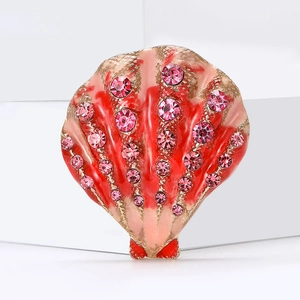 Macro shot of seashell brooch with red enamel gradient and sparkling pink rhinestones