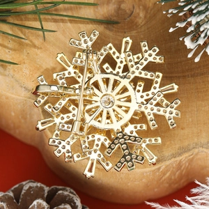 Luxury gold snowflake brooch with zircon on rustic wood and festive red background