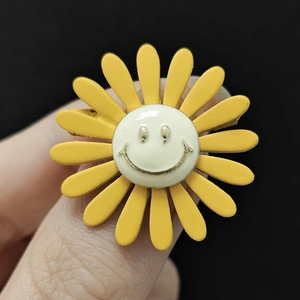 Macro-opname van een gele zonnebloem broche met gouden lachend gezicht op zwarte achtergrond
