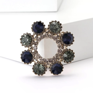 Macro view of crystal wreath brooch with blue and green gems on golden alloy base