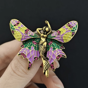 Detail of vintage angel brooch with purple enamel wings and pink rhinestones on gold alloy