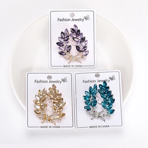 Detail of three crystal leaf brooches in purple, gold, and blue with rhinestone bows