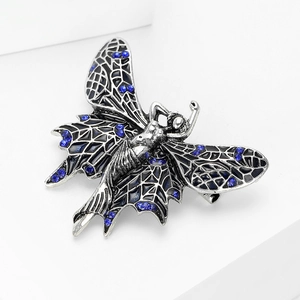 Macro detail of silver angel wings brooch with dark blue rhinestones and black enamel
